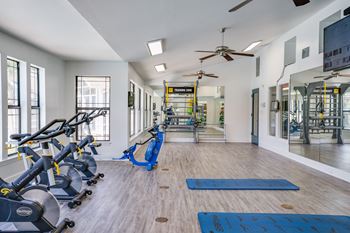 a gym with cardio machines and yoga mats and a ceiling fan at The Monroe Apartment Homes, Tallahassee, FL